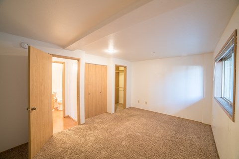 a living room with carpet and a door to a bedroom