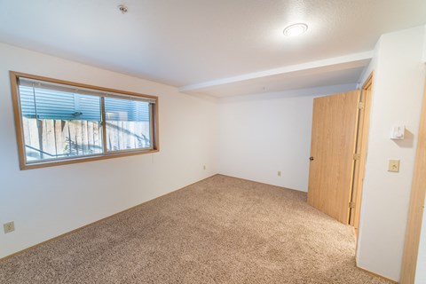an empty living room with a window and a door