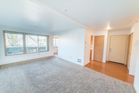 an empty living room with a large window and a door