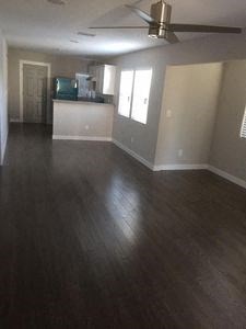 an empty living room and kitchen with wood floors