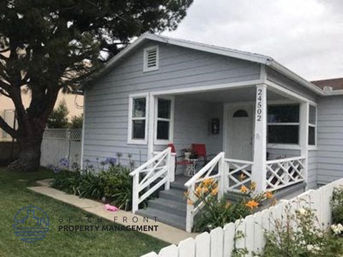 a small house with a porch and a white fence