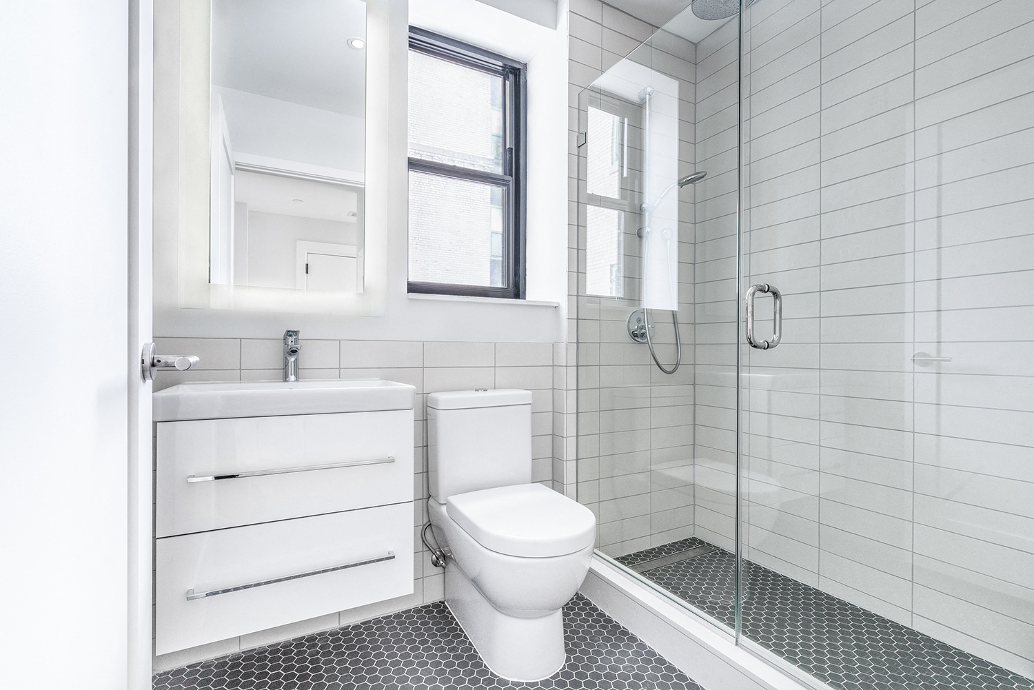 Bright tiled bathrooms with large backlit designer mirror, Hans Grohe chrome fixtures and Villeroy & Boch vanity