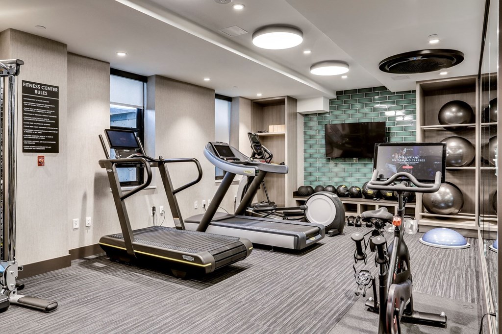 a gym with treadmills and bikes and a tv on the wall