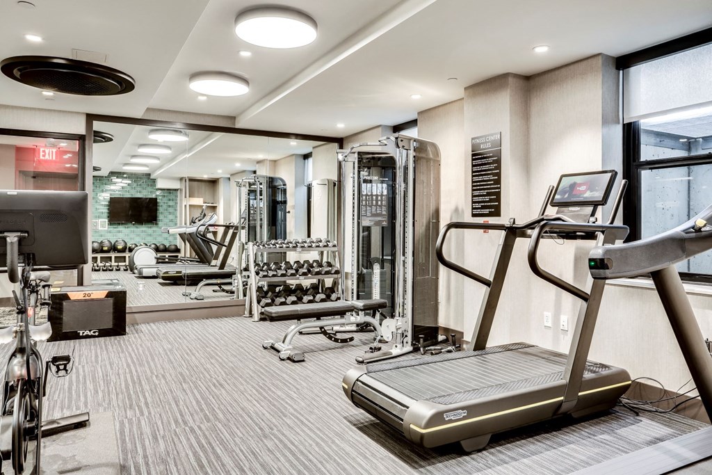 a gym with cardio equipment and a large window
