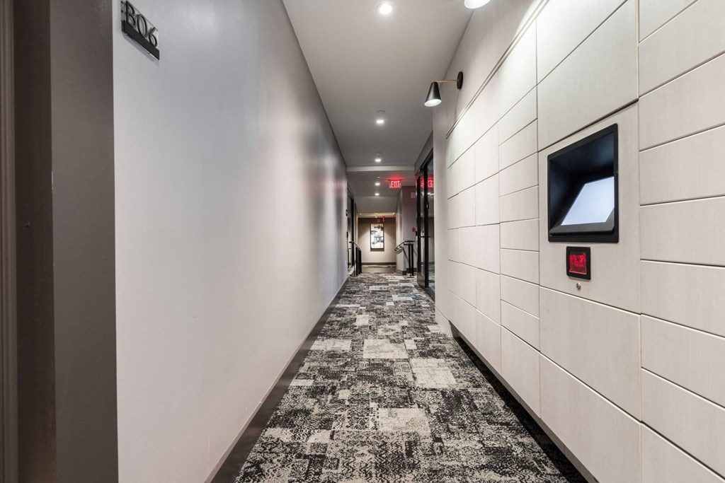 a hallway with white walls and a carpeted floor and a television