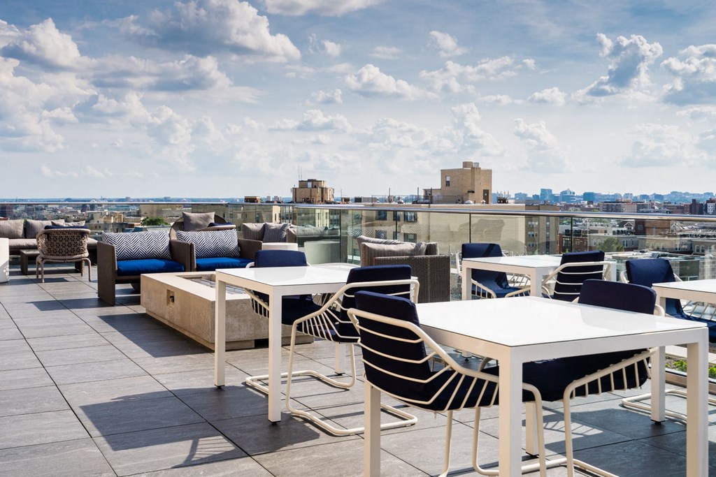 a rooftop terrace with tables and chairs and a view of the city