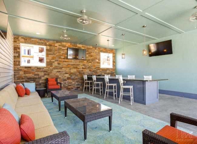 a living room with a couch and chairs and a bar