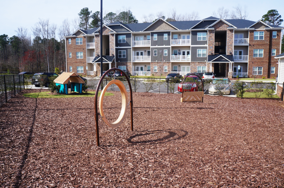 an empty playground with a swing set in front of an apartment building