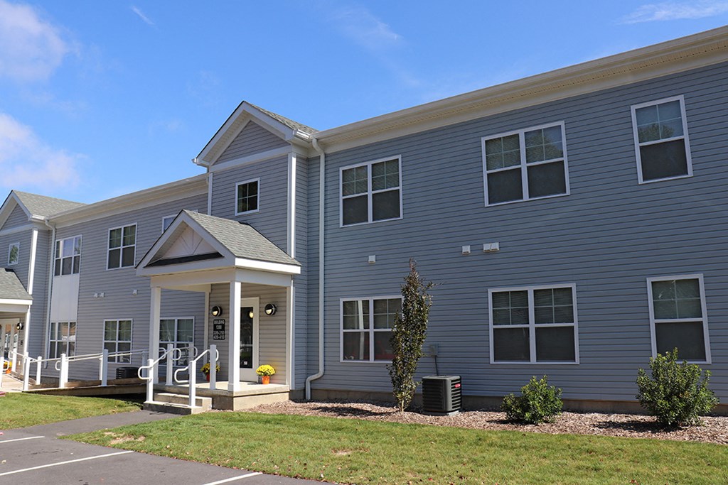 a blue apartment building with a porch and a lawn