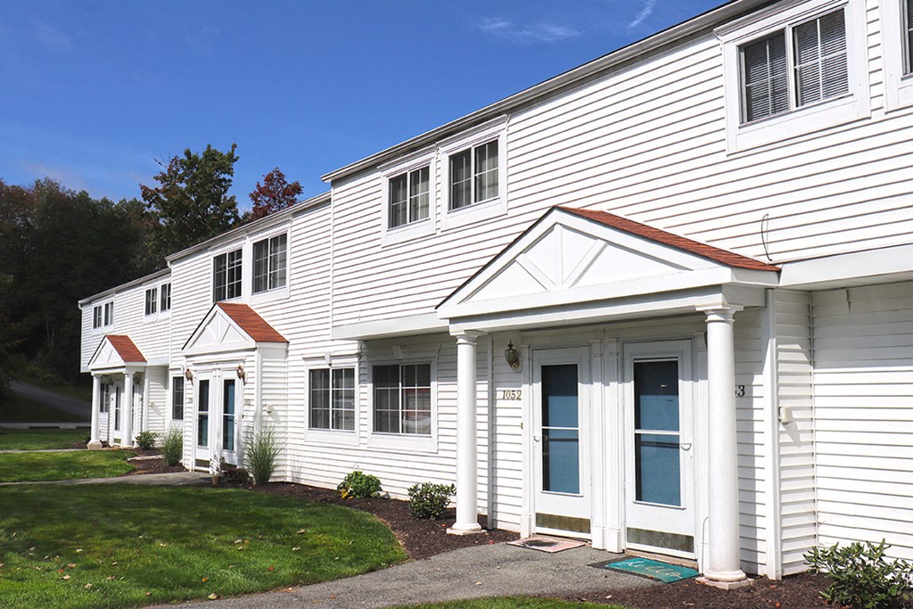 a white building with white siding and a sidewalk