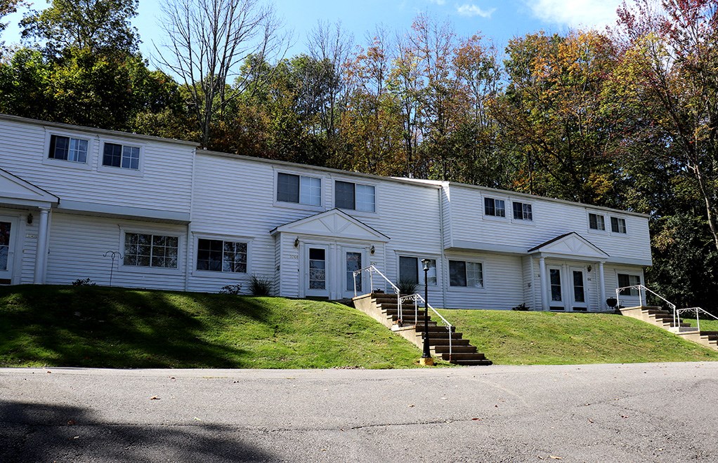 a white house on a hill with trees