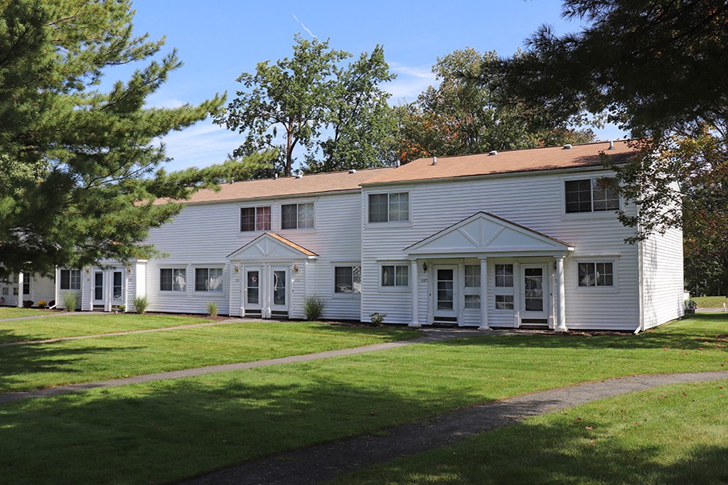 a white house with a lawn and trees