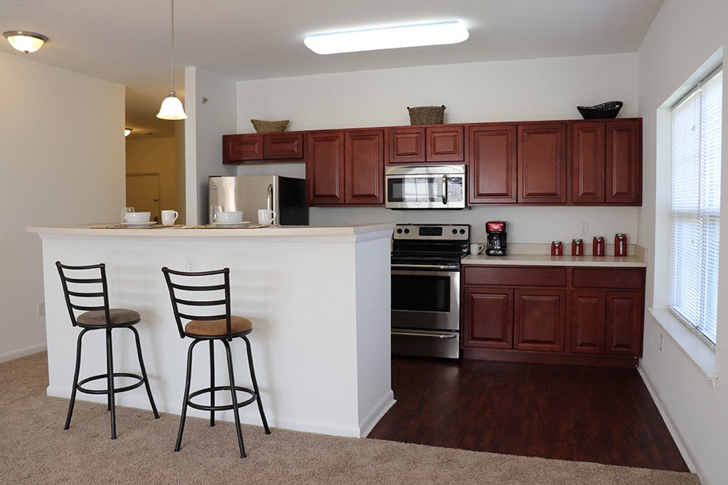 a kitchen with a counter with two chairs and a