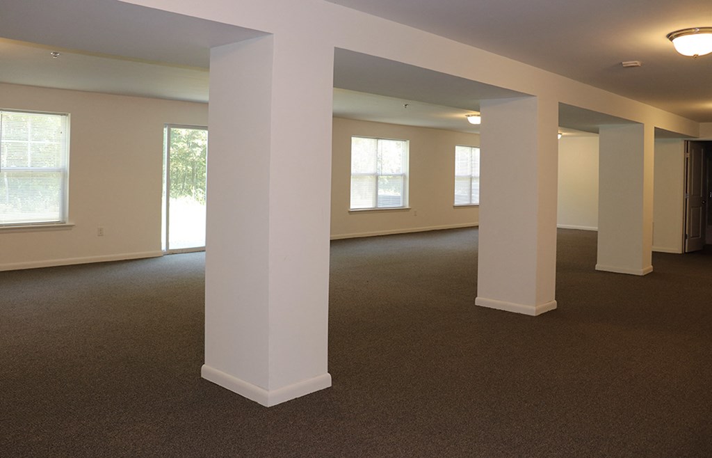 an empty living room with pillars and windows