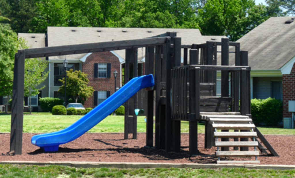 A playground with a blue slide and wooden structure.