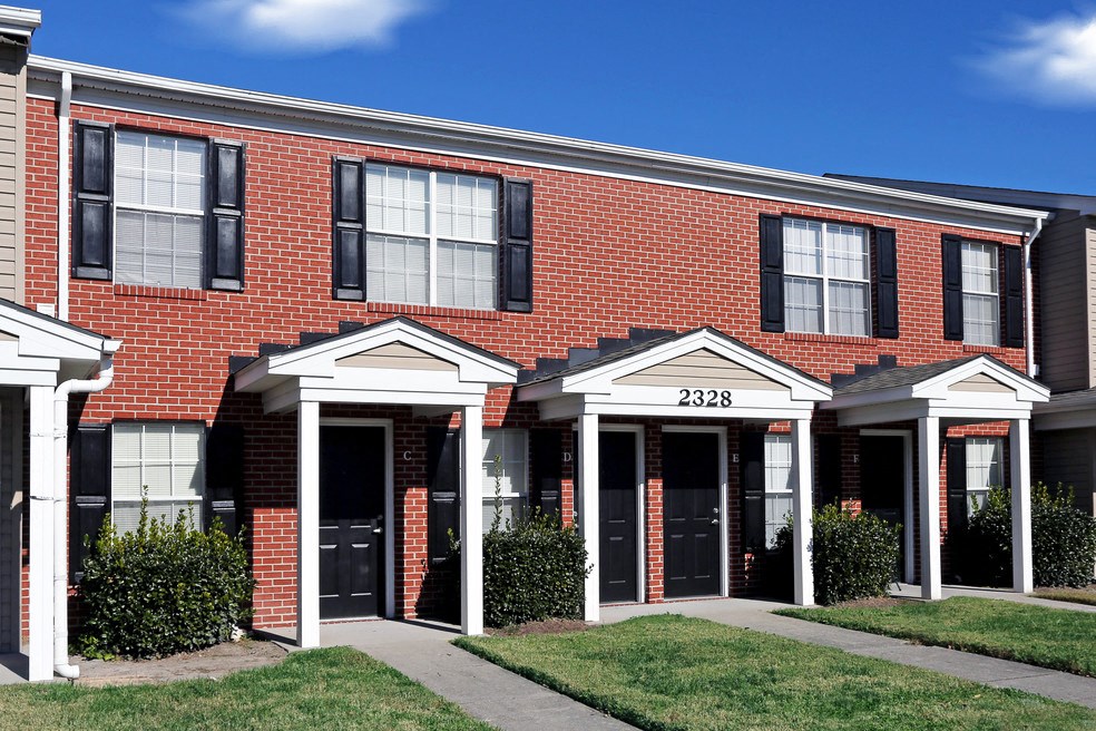 the front of a brick building with black windows and a sidewalk