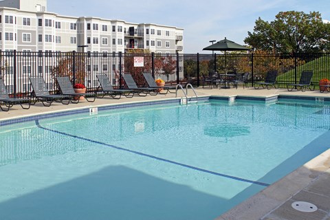 a swimming pool with chairs and a fence around it