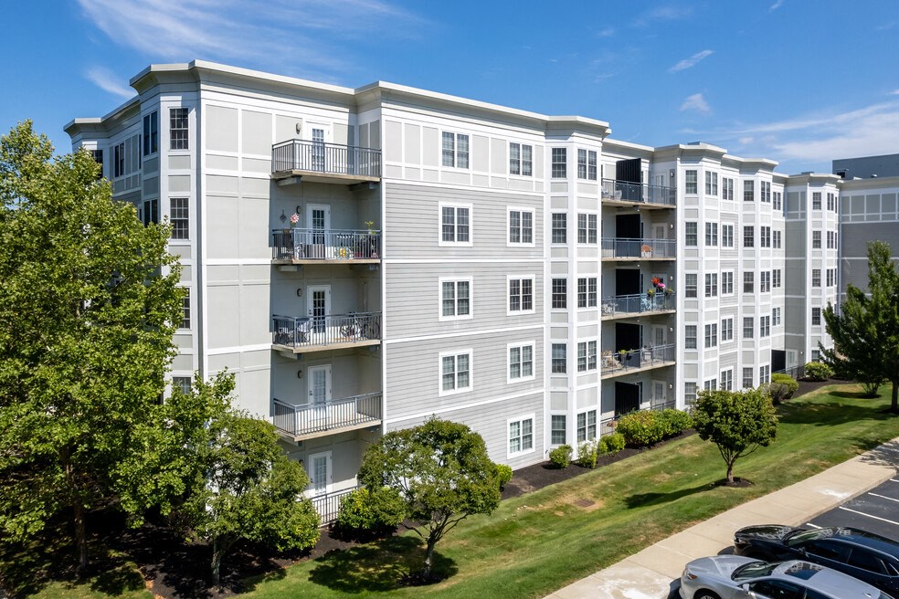 an exterior view of an apartment building with trees and a parking lot
