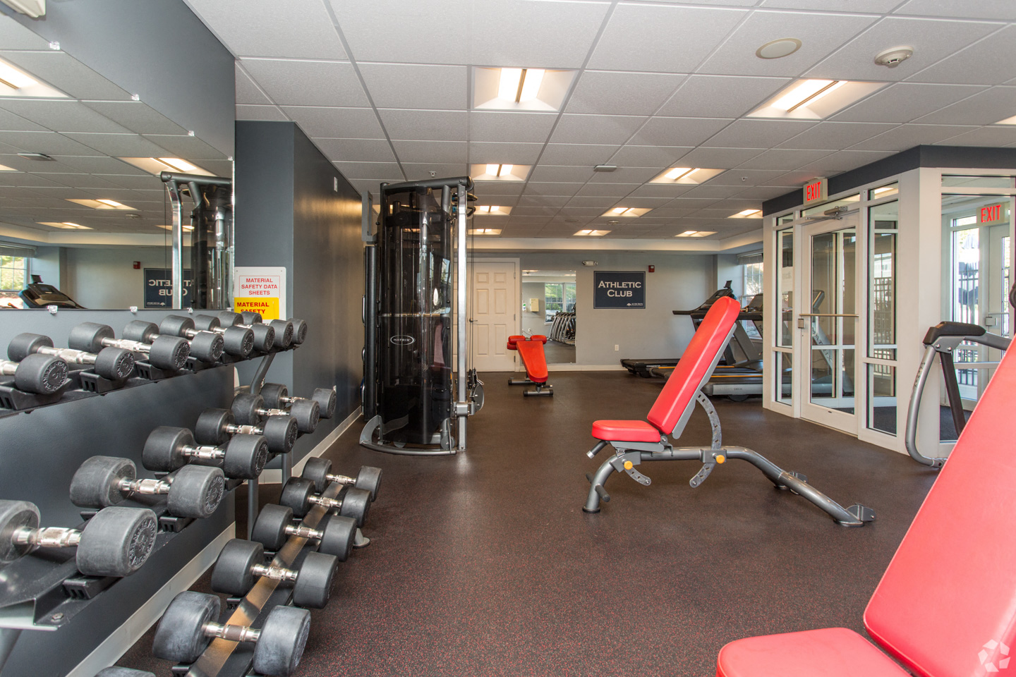 a gym with weights and other equipment on the floor and a glass door
