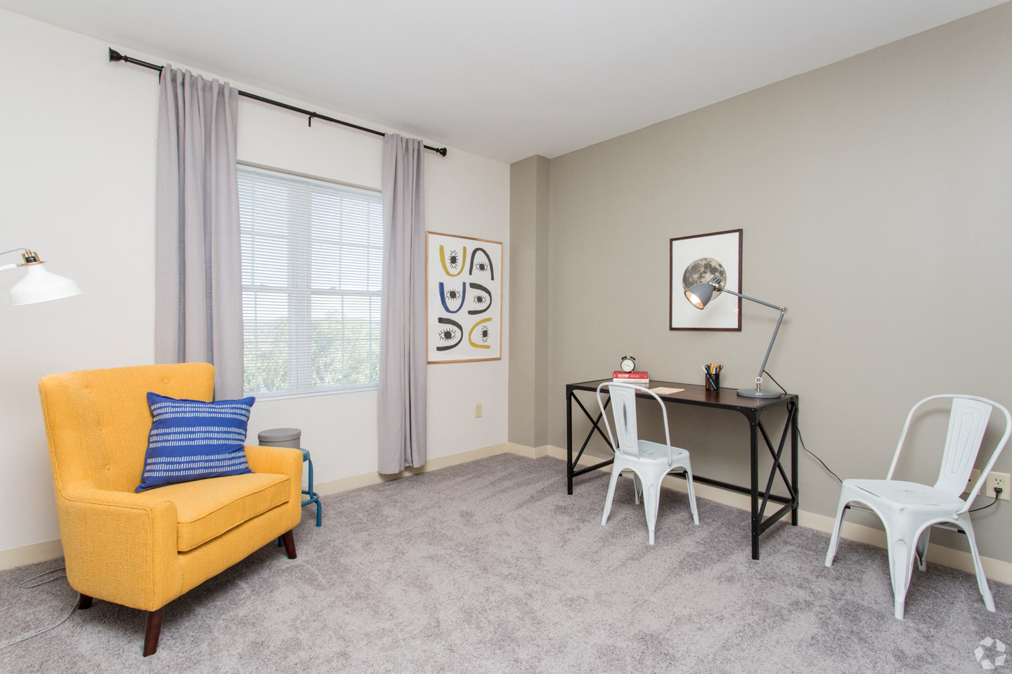 a living room with a desk and a chair and a window