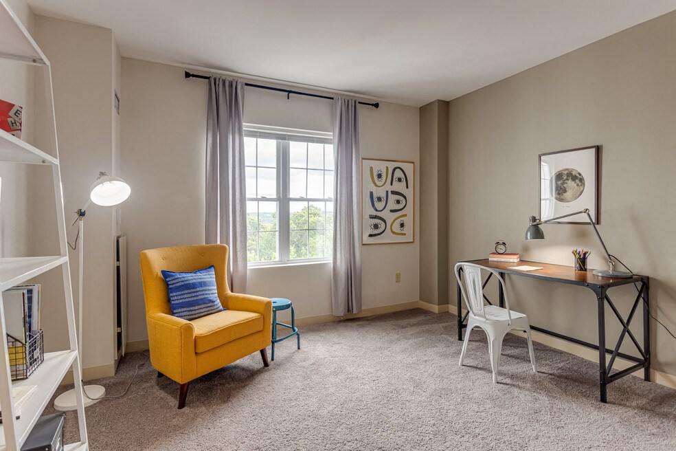 a living room with a desk and a chair and a window