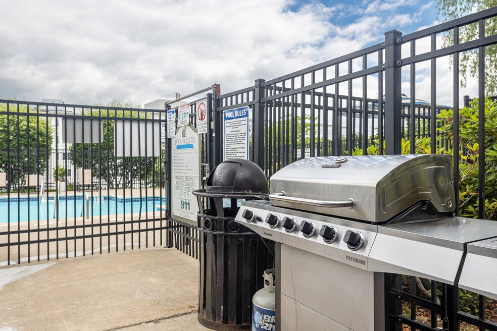 a gas grill with a swimming pool in the background