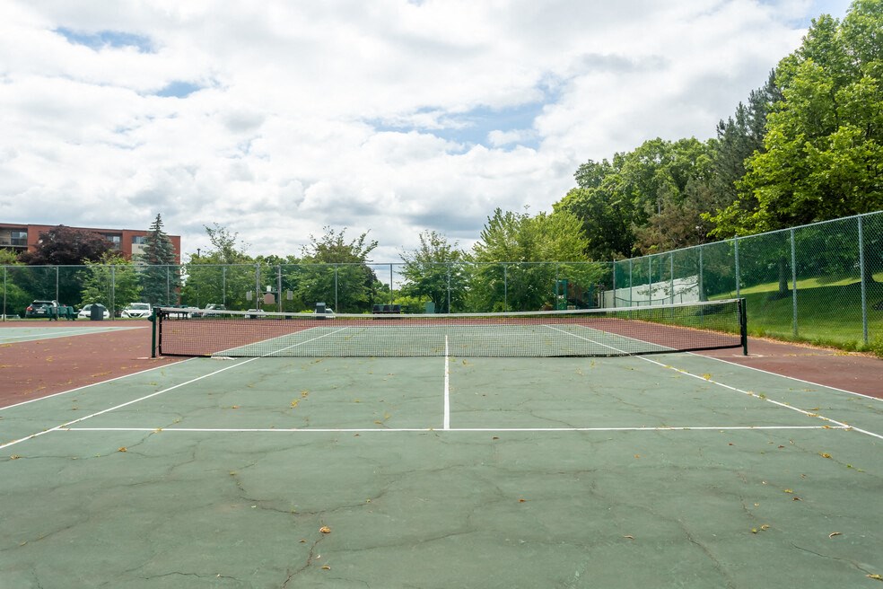 a tennis court with a fence around it and trees