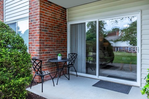 a patio with two chairs and a table in front of a window