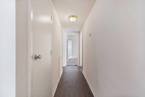 a hallway with white walls and a door leading to a bedroom