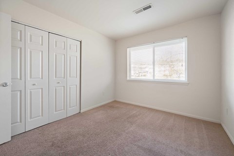 an empty room with a window and a closet