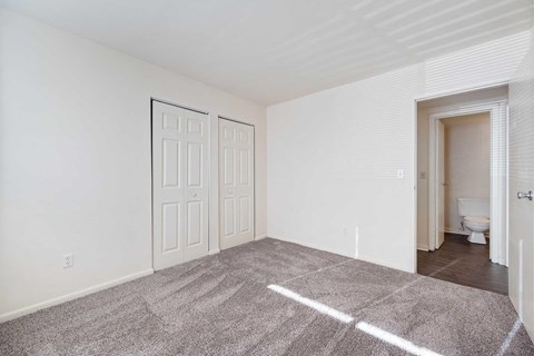 an empty bedroom with a door to the bathroom