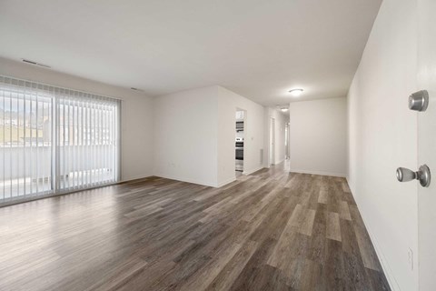 an empty living room with wood flooring and sliding glass doors