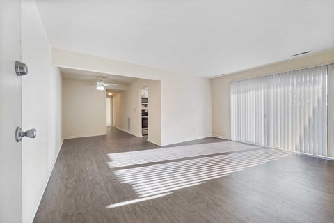 an empty living room with a sliding glass door to a bedroom