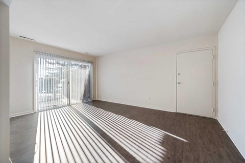 an empty living room with a door to a balcony