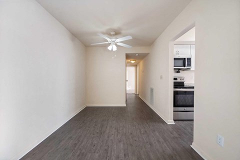 an empty living room with a ceiling fan and a kitchen
