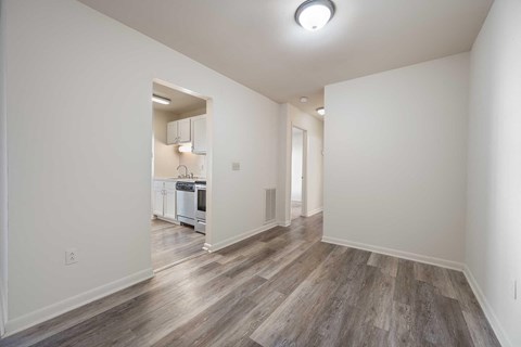 a renovated living room and kitchen with white walls and wood floors