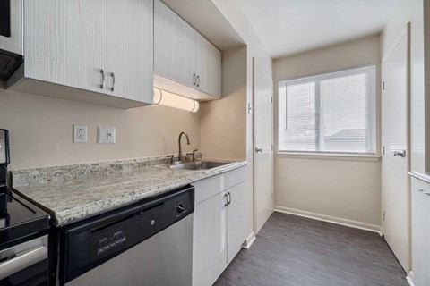 a kitchen with white cabinets and a sink and a window