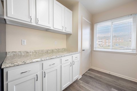 a white kitchen with white cabinets and a window