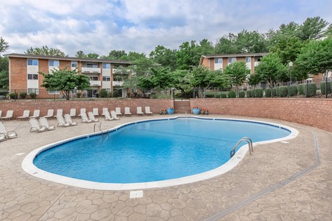 a swimming pool with chairs around it in front of an apartment building