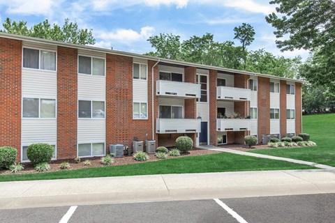 an exterior view of a brick apartment building with green grass and trees