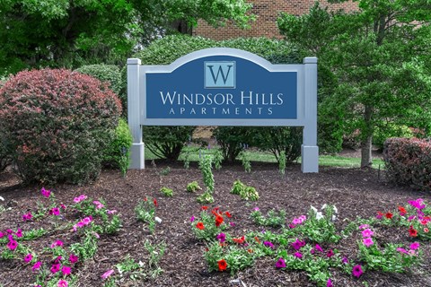 a sign for windsor hills apartments in front of flowers