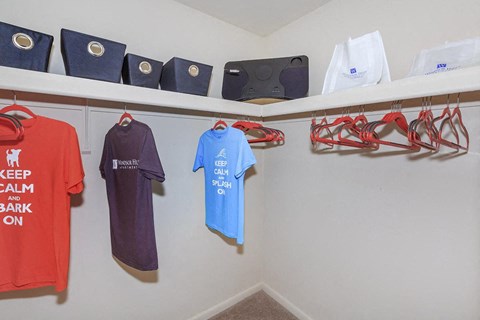 a laundry room with shirts and hangers on the wall and a closet with clothes