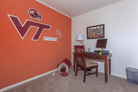 a home office with a desk and a wall with a vt logo