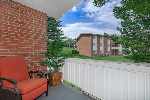 a balcony with an orange chair and a brick building