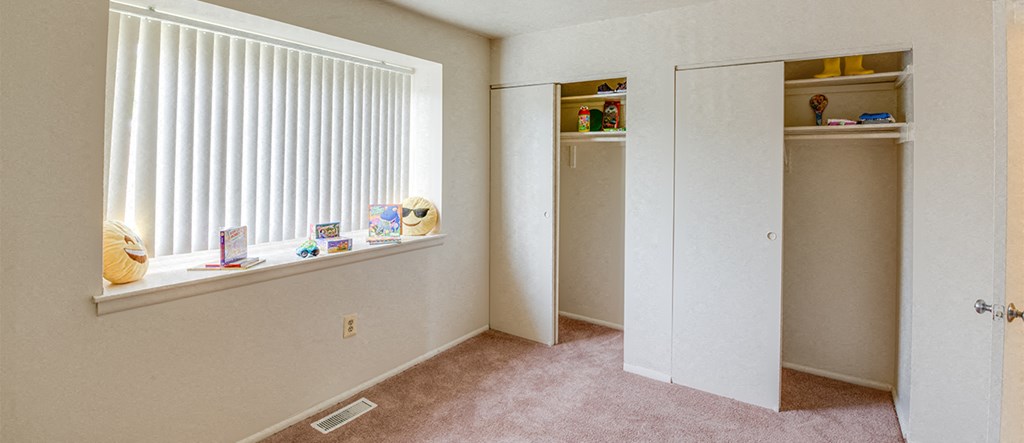 a bedroom with a closet and a window with toys on the window sill