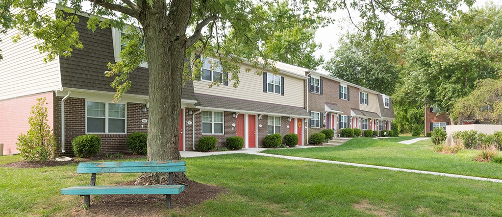a blue bench sitting under a tree in front of houses