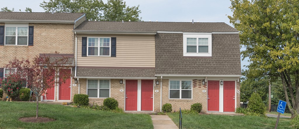 a brick house with red doors and a sidewalk