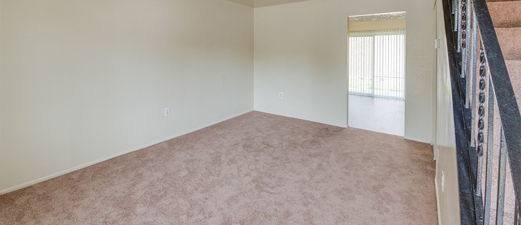 an empty living room with white walls and carpet