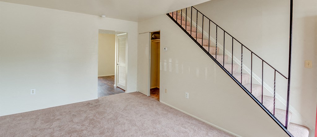an empty living room with a staircase in a home with white walls