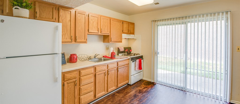 a kitchen with wood cabinets and white appliances and a sliding glass door